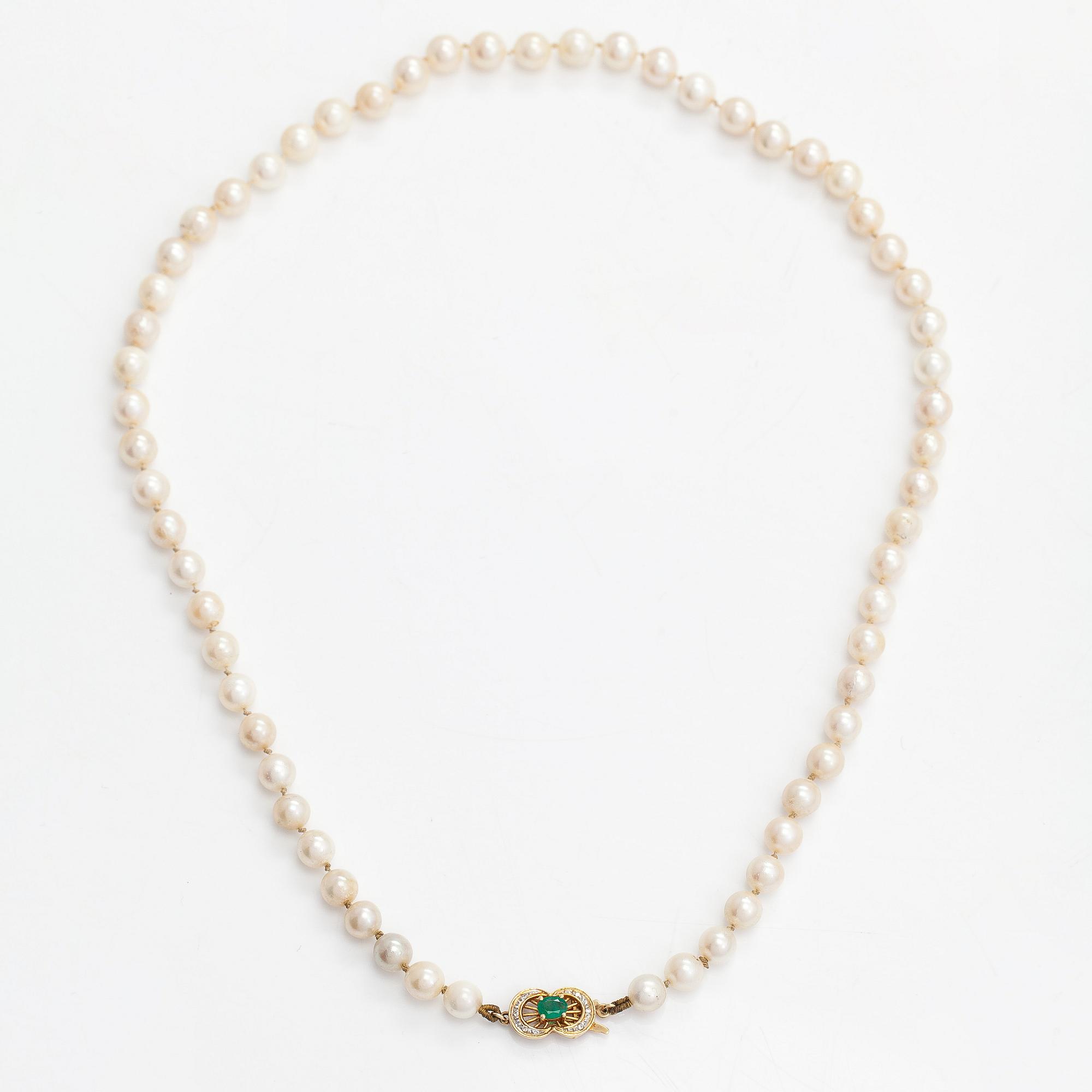 A cultured pearl necklace, clasp 18K gold with emerald and small diamonds.