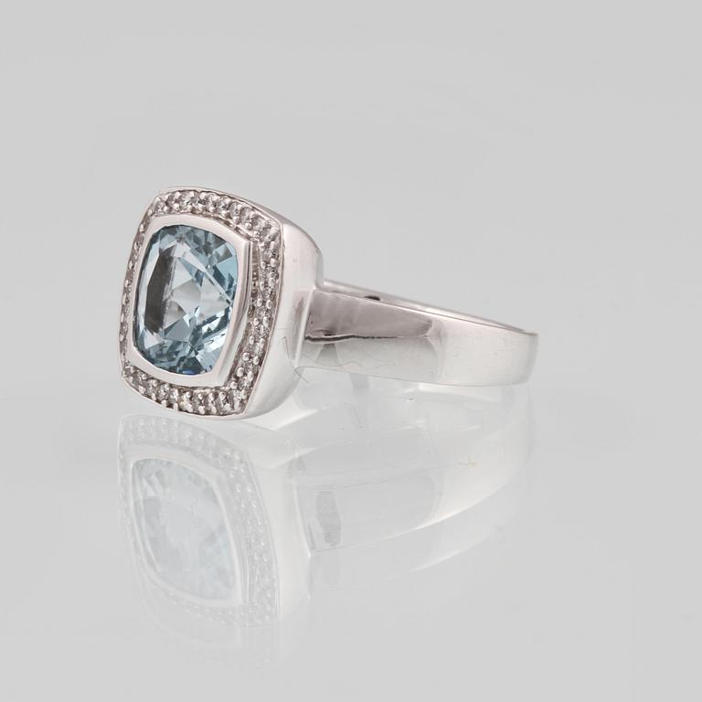 RING, 18K vitguld med fasettslipad blå topas samt 36 briljantslipade diamanter, ca 0.18 ct. Vikt 8,2 gram.