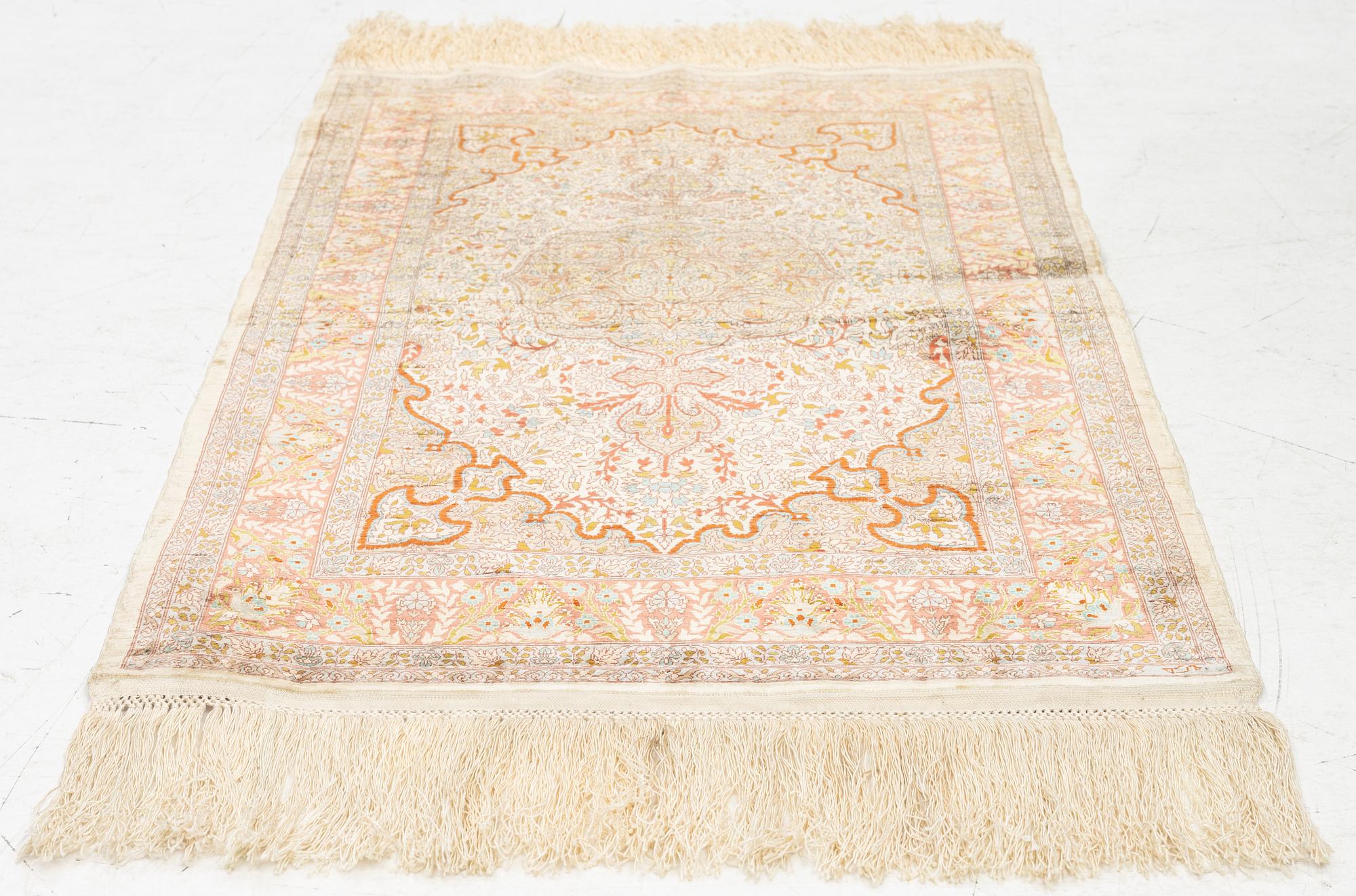 A silk Hereke rug, c. 85 x 55 cm.