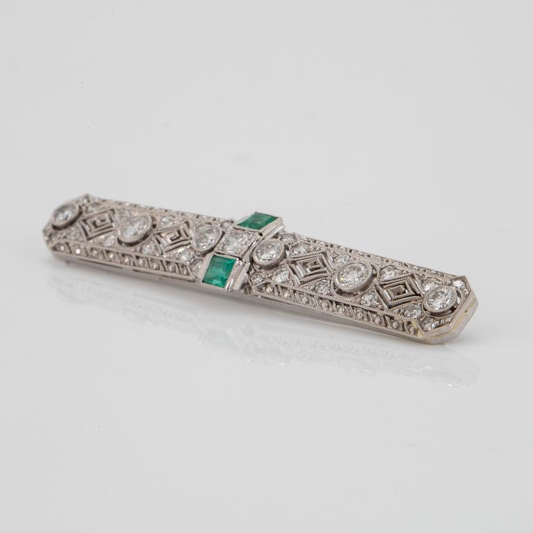 An 18K white gold brooch set with old- and eight-cut diamonds and faceted emeralds.