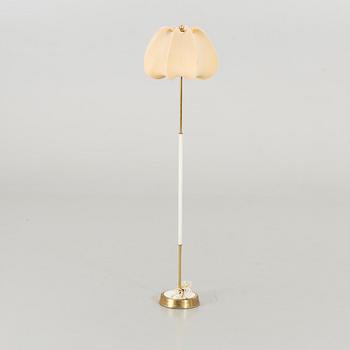 A brass floor light with white fabric lamp-shade.