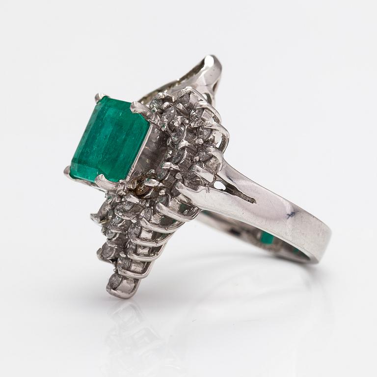 A platinum ring with a ca. 3.20 ct emerald and diamonds ca. 1.16 ct in total.