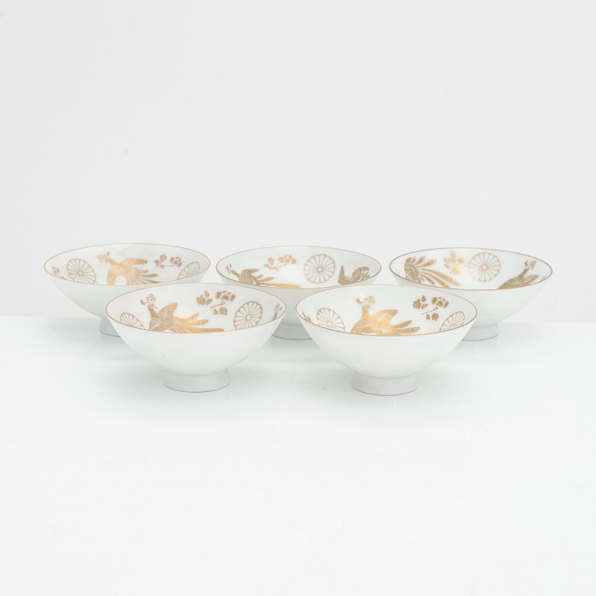 Five porcelain sake cups and a papier maché doll, Japan first half of the 20th century.