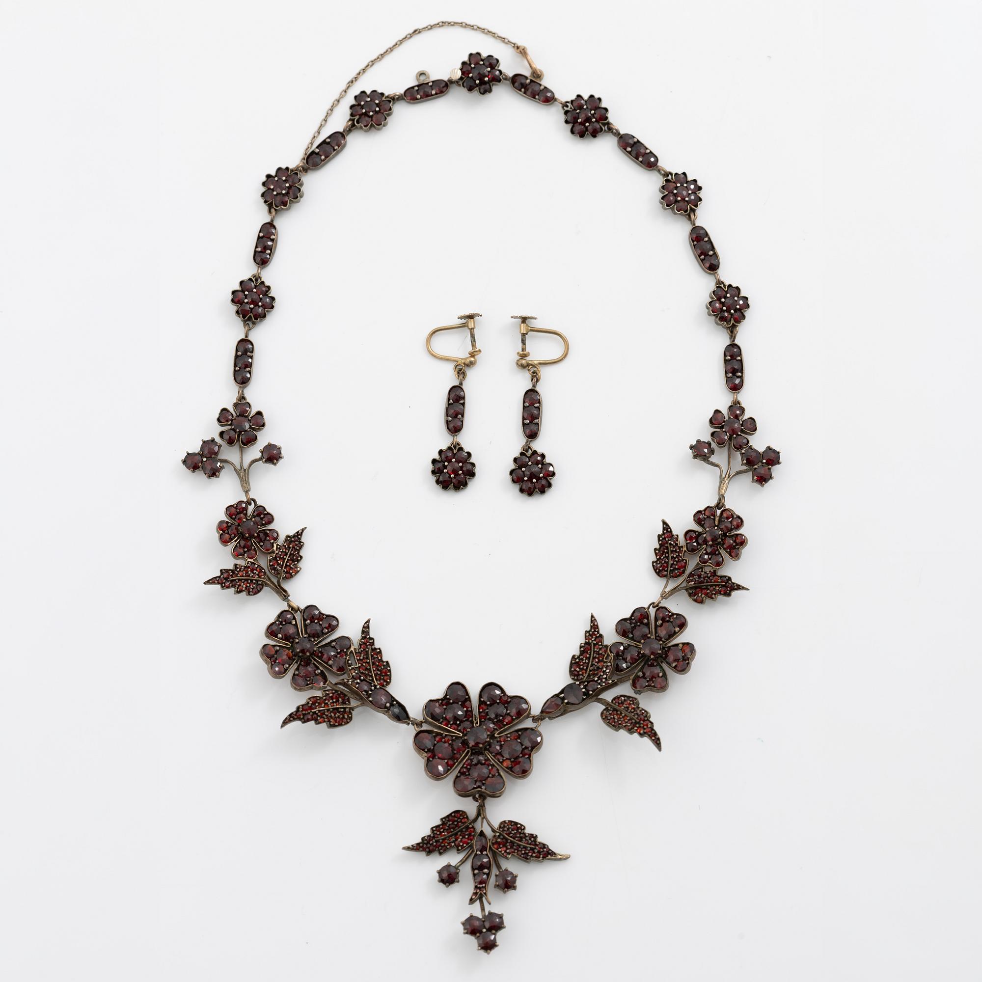 Garniture, necklace/bracelet and earrings in silver with garnets in the form of floral motifs, around the turn of the 20th century.