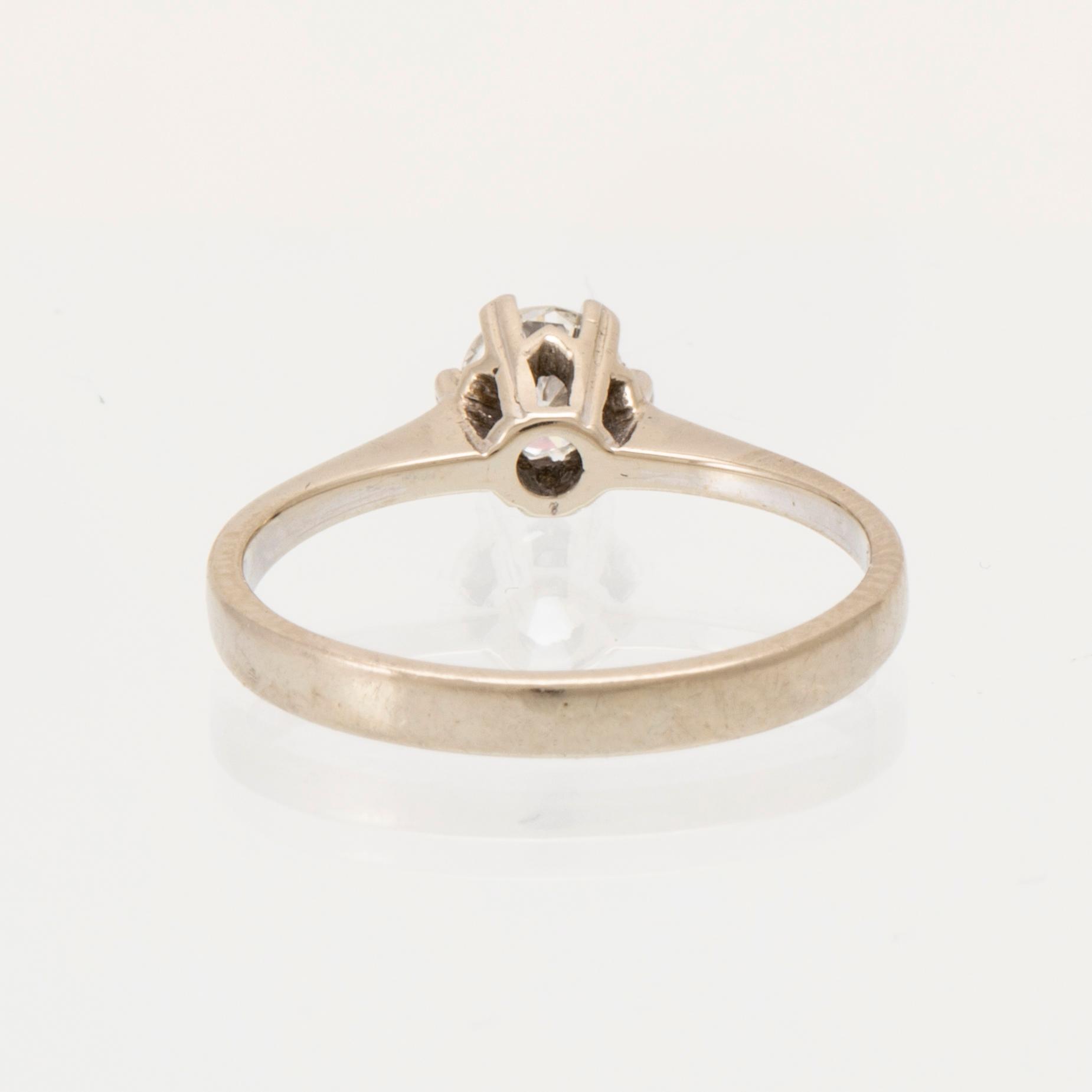 An 18K white gold solitaire ring set with a round brilliant-cut diamond.