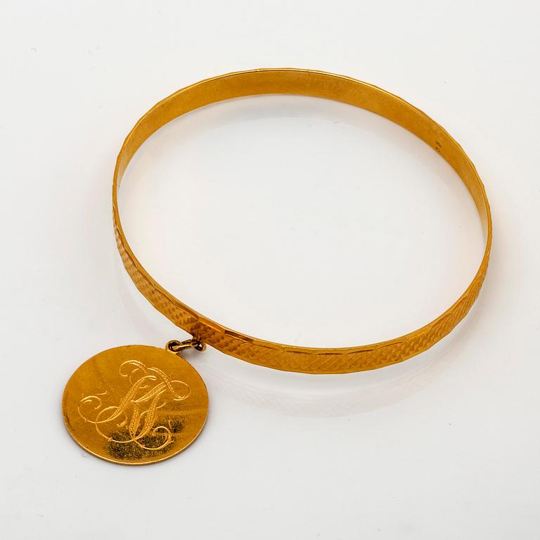Bangle 18k gold with 1 charm, 19,3 g, does not open.