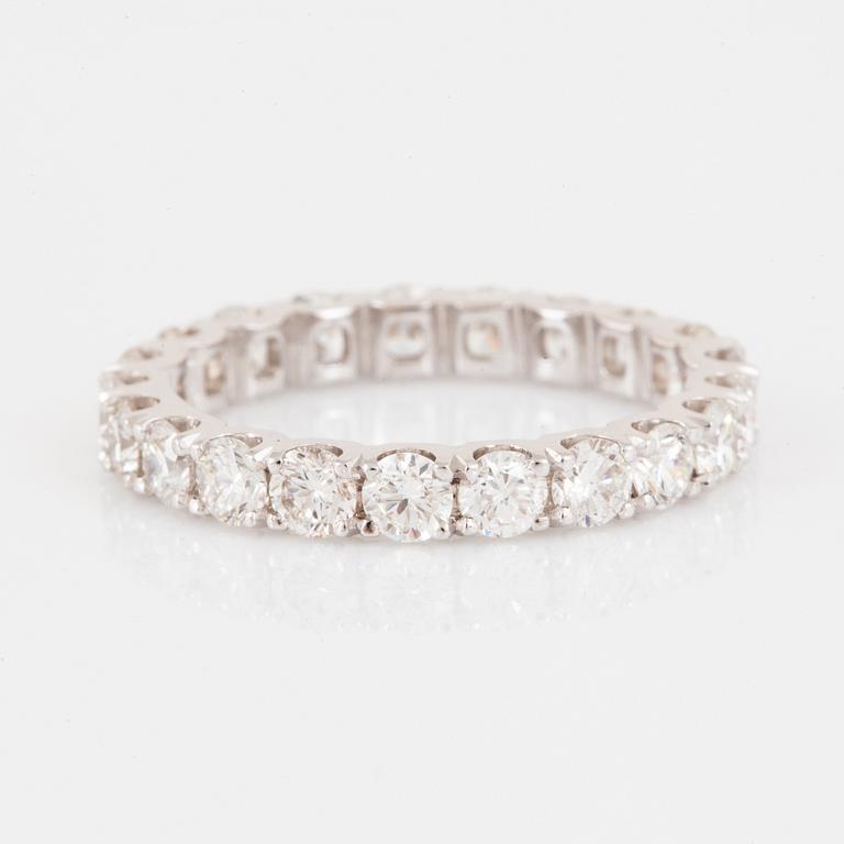 An 18K gold eternity ring set with round brilliant-cut diamonds.