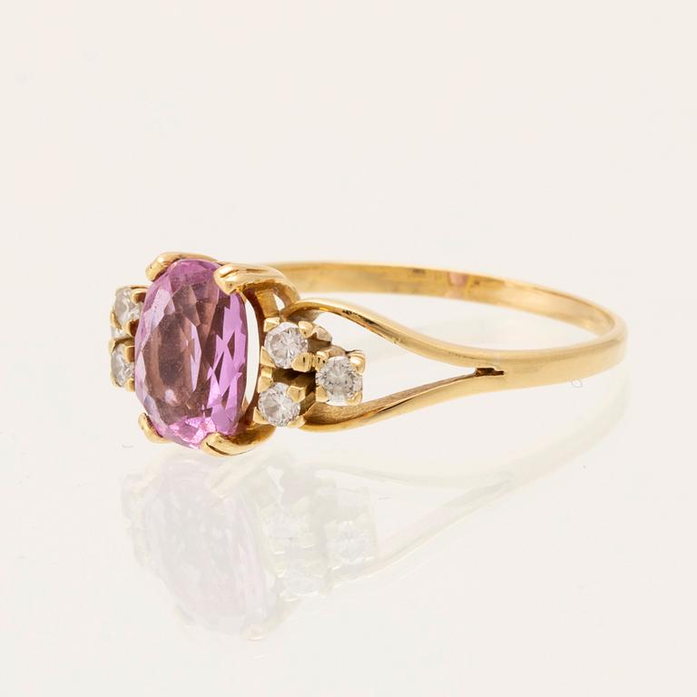 An 18K gold ring set with an oval faceted pink gemstone and round brilliant-cut diamonds.