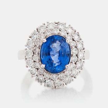 An 18K white gold ring set with an oval faceted sapphire and round brilliant-cut diamonds.