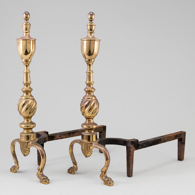 A pair of  ornate brass urn top cast iron fireplace fire dog andirons from around the year 1900.