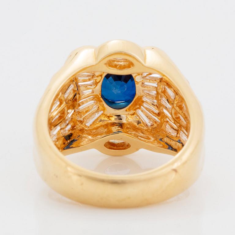 An 18K gold Junod ring set with a facted sapphire and tapered baguette-cut diamonds.