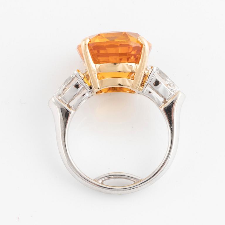 An 18K white gold ring set with a cushion shaped orange-yellow sapphire.