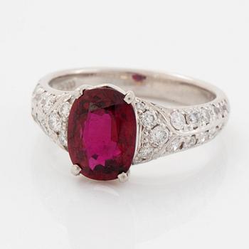 A platinum ring set with a faceted ruby and round brilliant-cut diamonds.