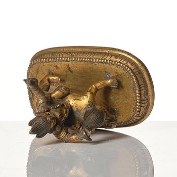 A small gilt bronze figure wrathful deity riding on a corpse, Tibeto-Chinese, 18th Century.