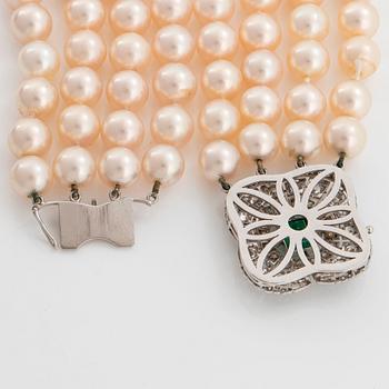 A four strand cultured pearl necklace with an 18K white gold clasp set with a faceted emerald.