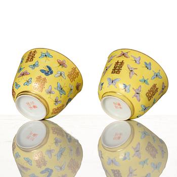 A pair of yellow glazed double happiness cups with butterflies, Qing dynasty, with Tongzhis four character mark to base.