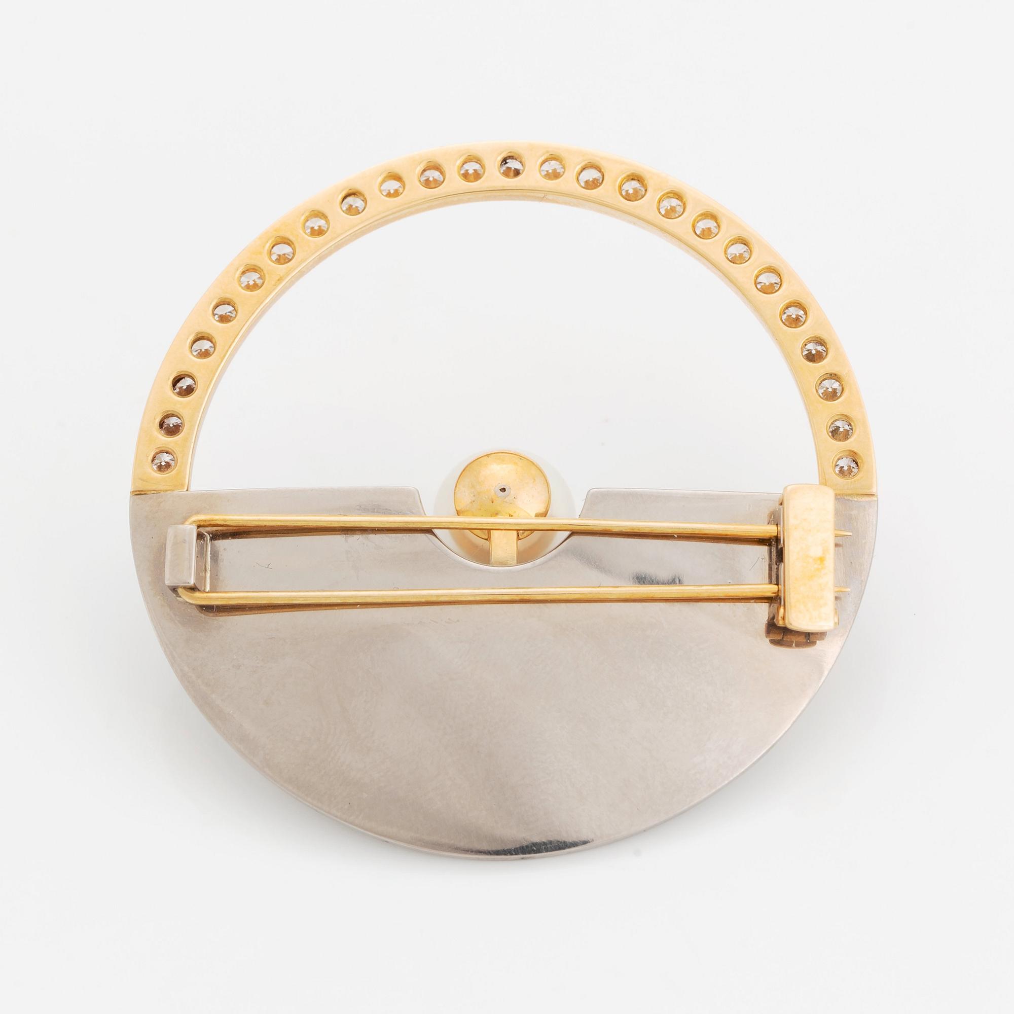 An 18K gold and white gold brooch set with a cultured pearl, round brilliant-cut diamonds and emeralds.