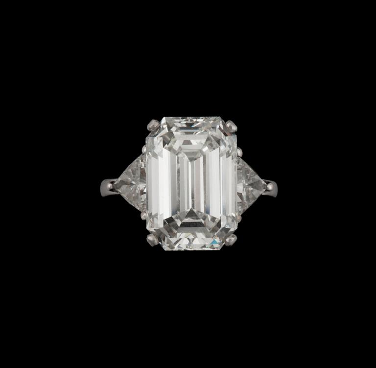 A baguette-cut diamond, 9.30 cts, ring. Quality I/VVS2. Flanked by two triangular diamonds approximately 1.00 ct each.