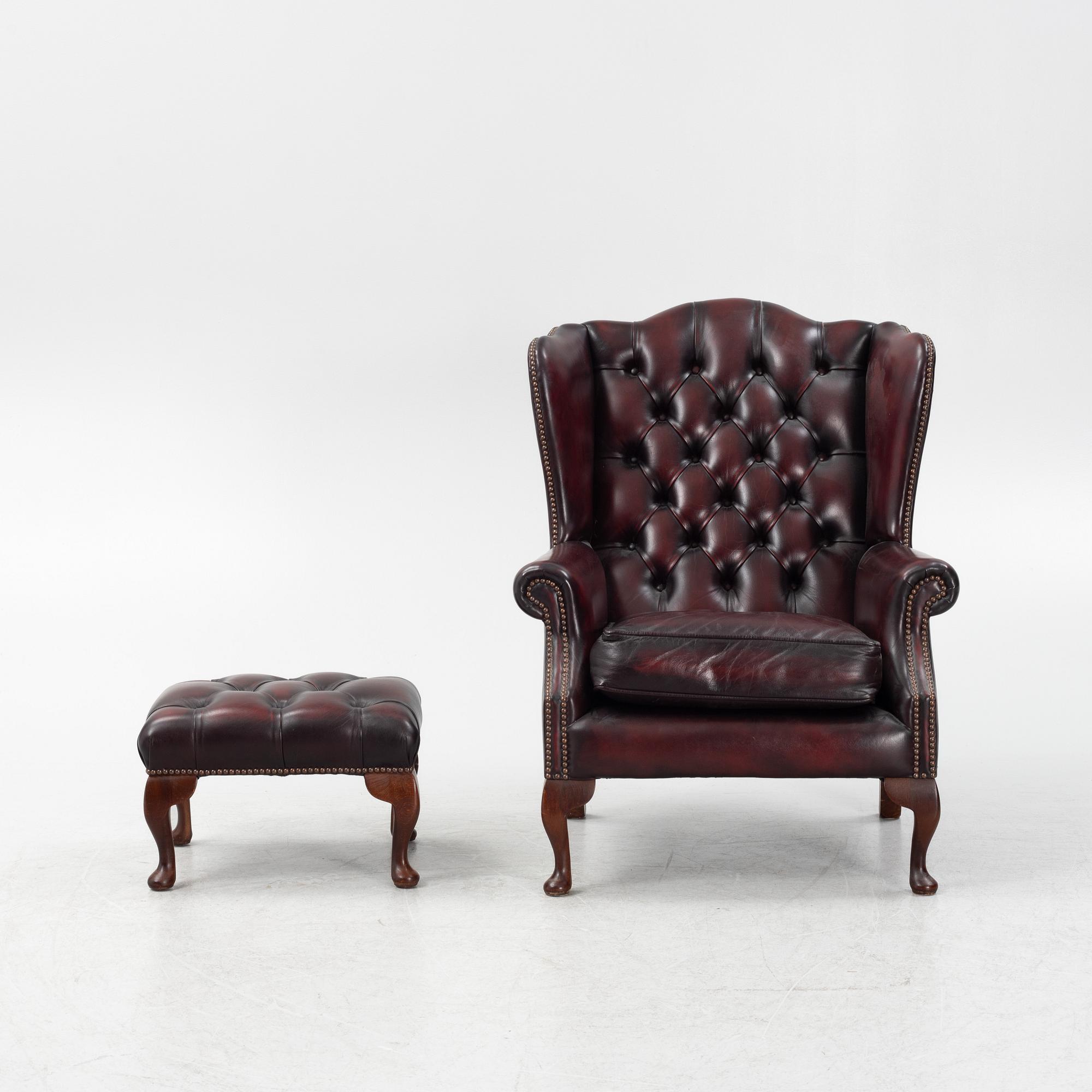 A leather upholstered wingback chair with stool. end of the 20th Century.