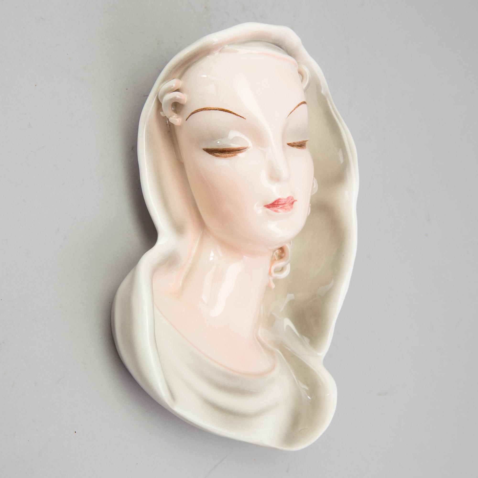A late 1930s porcelain Goldscheider wall mask, model 7894, marked "Goldscheider Wien" and Made in Germany.