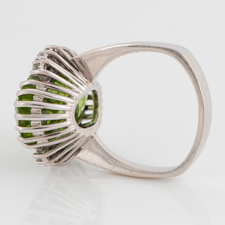 An 18K white gold ring set with an oval faceted peridot ca 11.00 cts and round brilliant-cut diamonds.