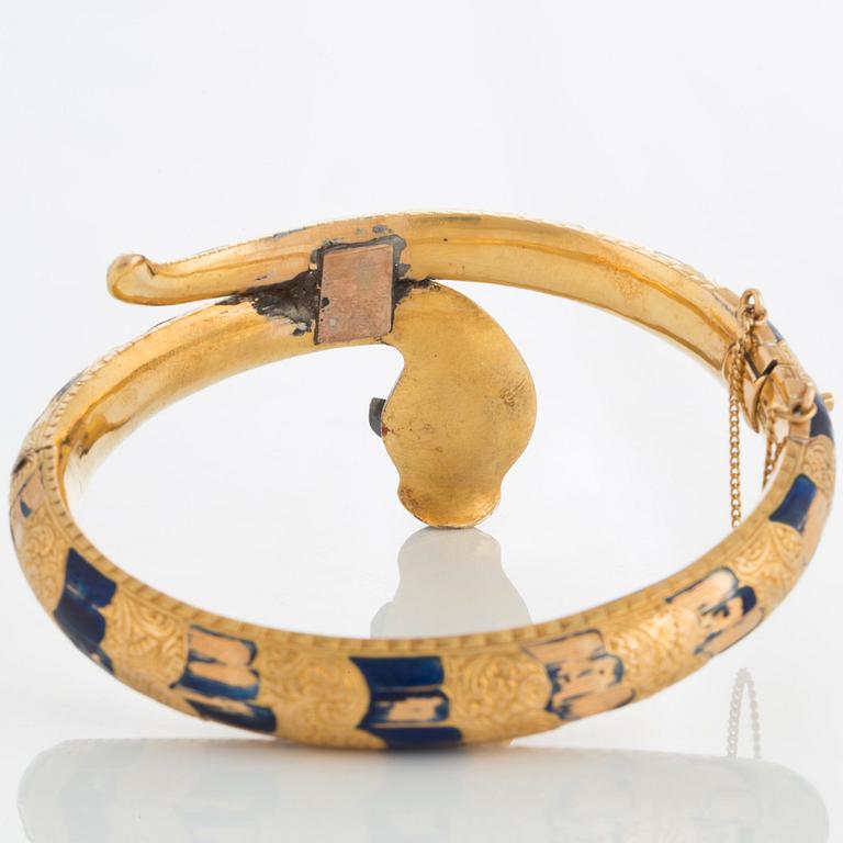 An 18K gold snake bangle decorated with blue enamel and set with an opal and a rose-cut diamond.