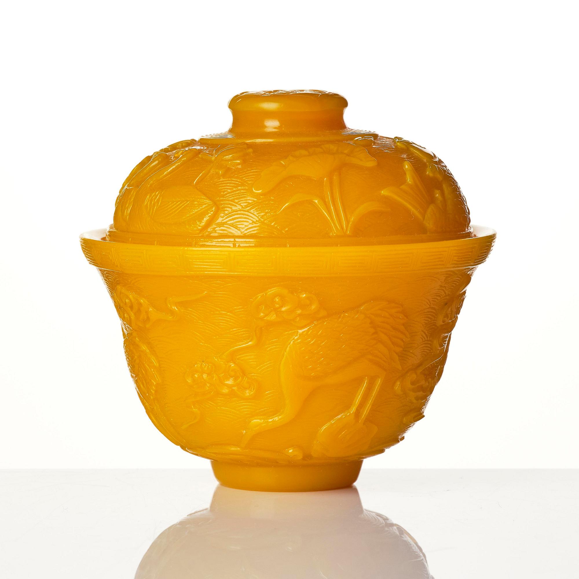 A well carved yellow glass 'crane and lotus' cup with cover, presumably late Qing dynasty.