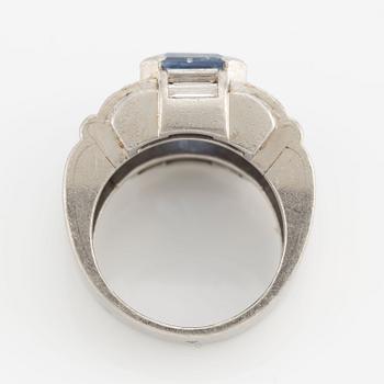 A platinum ring with a faceted sapphire and round brilliant-, eight-, and baguette-cut diamonds.