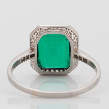 A platinum ring set with a Colombian step-cut emerald and old-cut diamonds in a fitted case from Cartier.