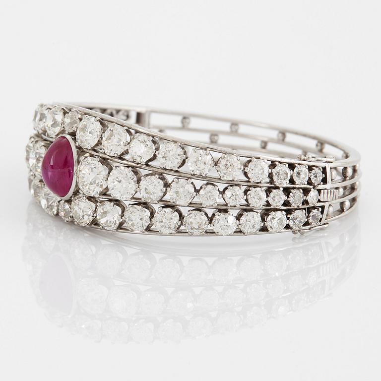 An 18K white gold bangle set with a cabochon-cut ruby and old-cut diamonds.