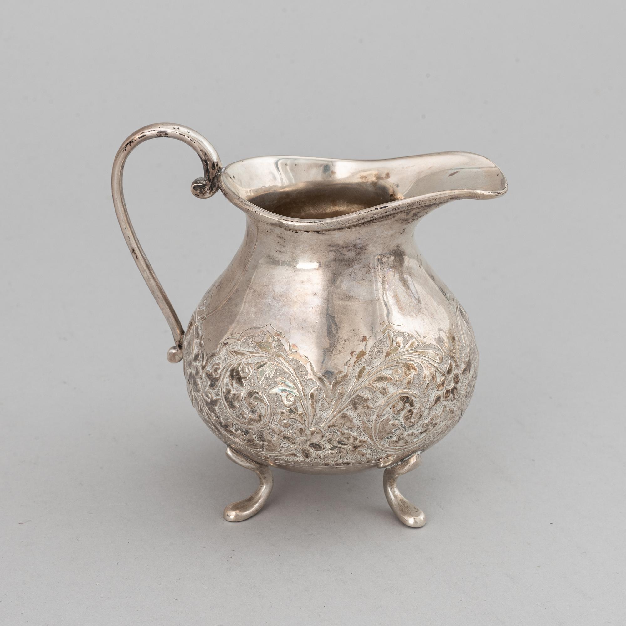 A Pakistan silver coffee pot, sugar bowl, sugar tongs and creamer.