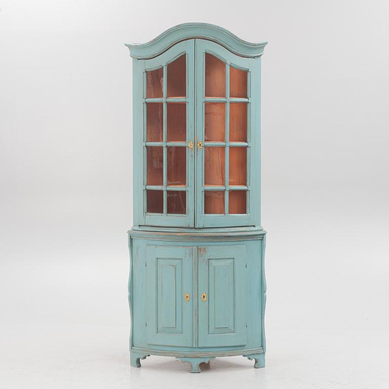 A corner display cabinet, 19th century with a later base.