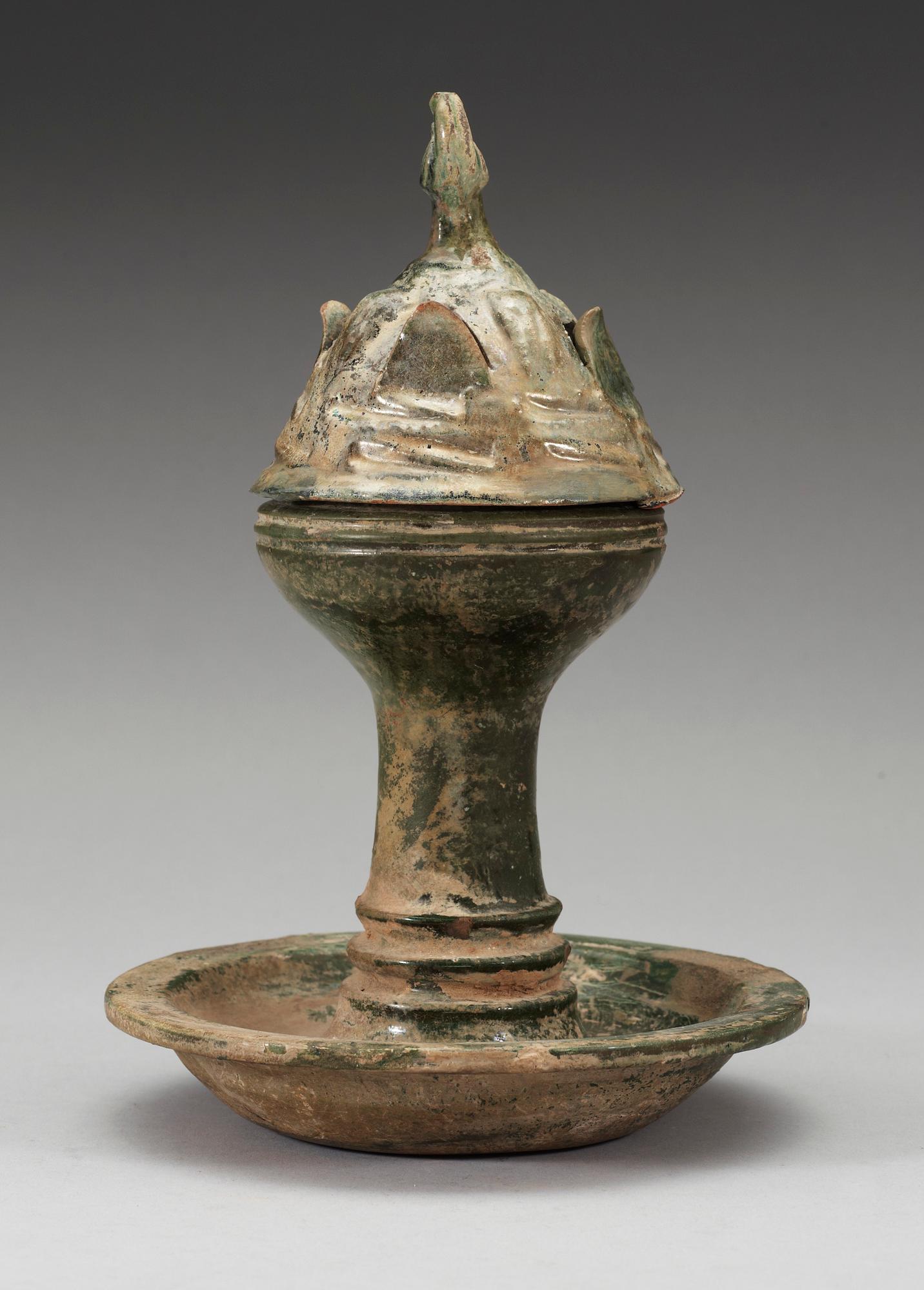 A green glazed pottery Hill Jar, cover with bird shaped finial, Han dynasty (206 BC-AD 220).