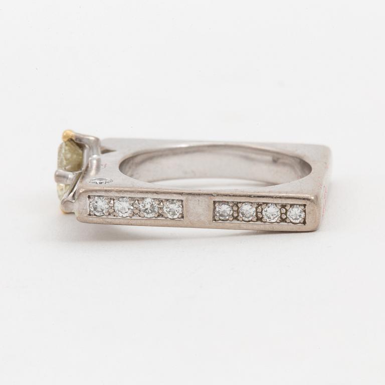 A ring set with a trilliant-cut diamond and small round, brilliant-cut diamonds.