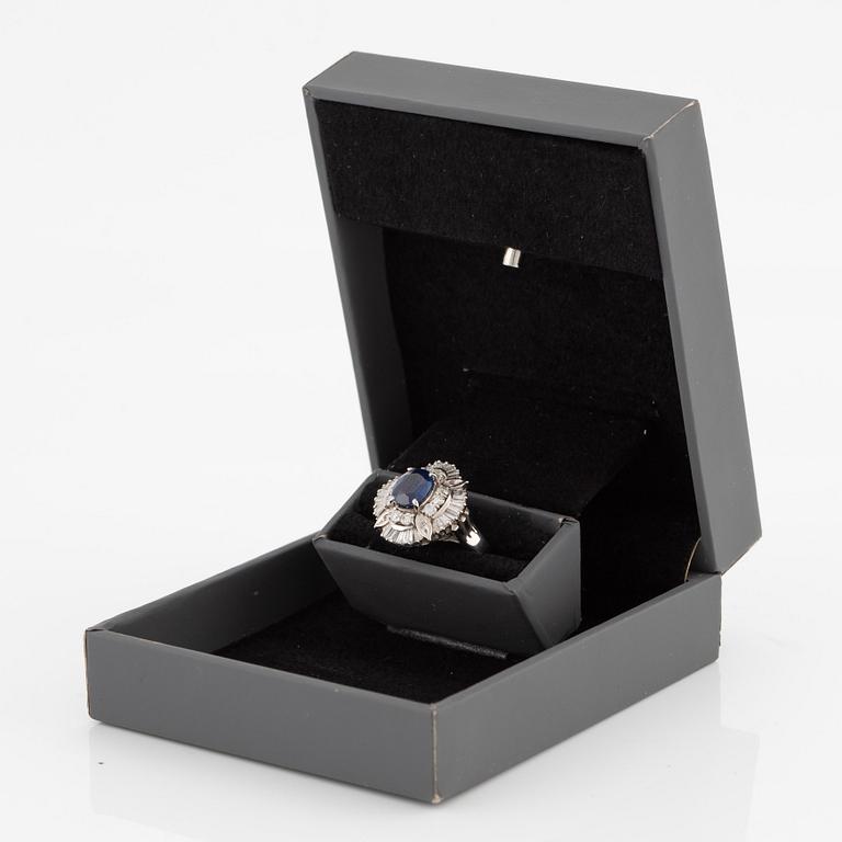 Ring in platinum set with a faceted sapphire and round brilliant- and baguette-cut diamonds.