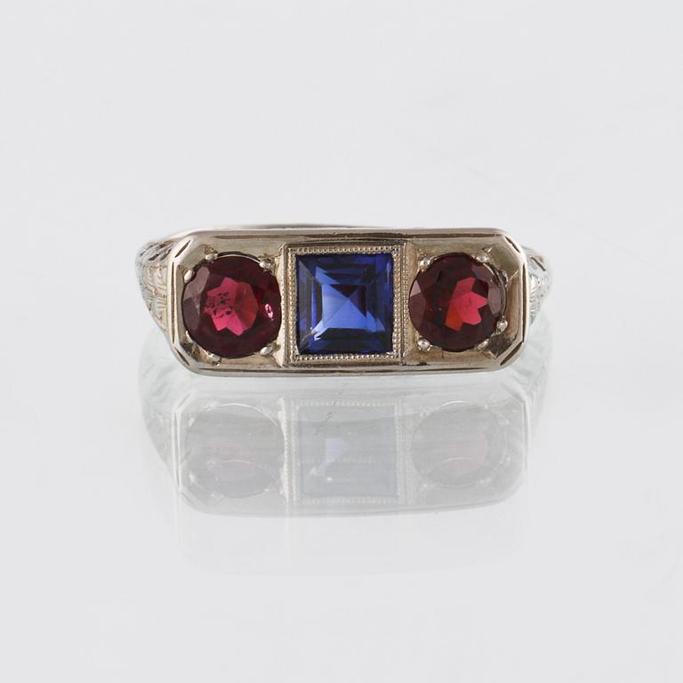 RING, 18K vitguld med fasettslipad blå safir samt 2 fasettslipade granater, utländska stämplar. Vikt 3,6 gram.