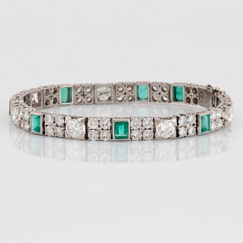 A platinum bracelet set with round brilliant- and old-cut diamonds and faceted emeralds.