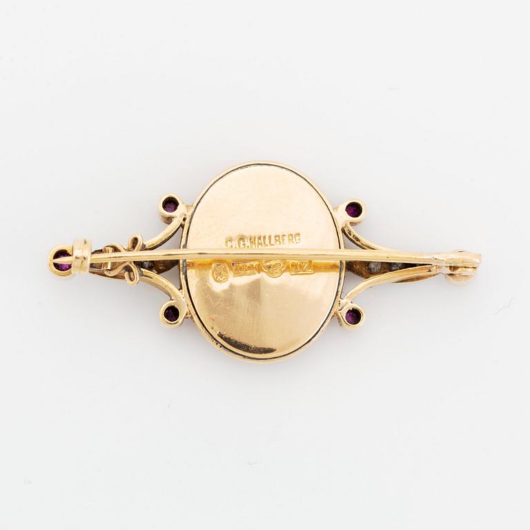 An 18K gold and enamel brooch set with rose-cut diamonds and faceted rubies.