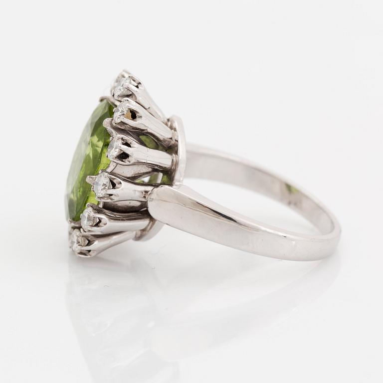 An 18K white gold ring set with a faceted peridot and round brilliant-cut diamonds.