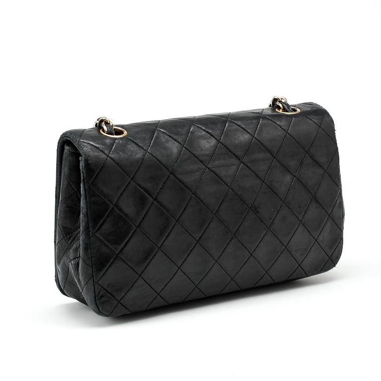 CHANEL, a black leather quilted purse with shoulder strap.