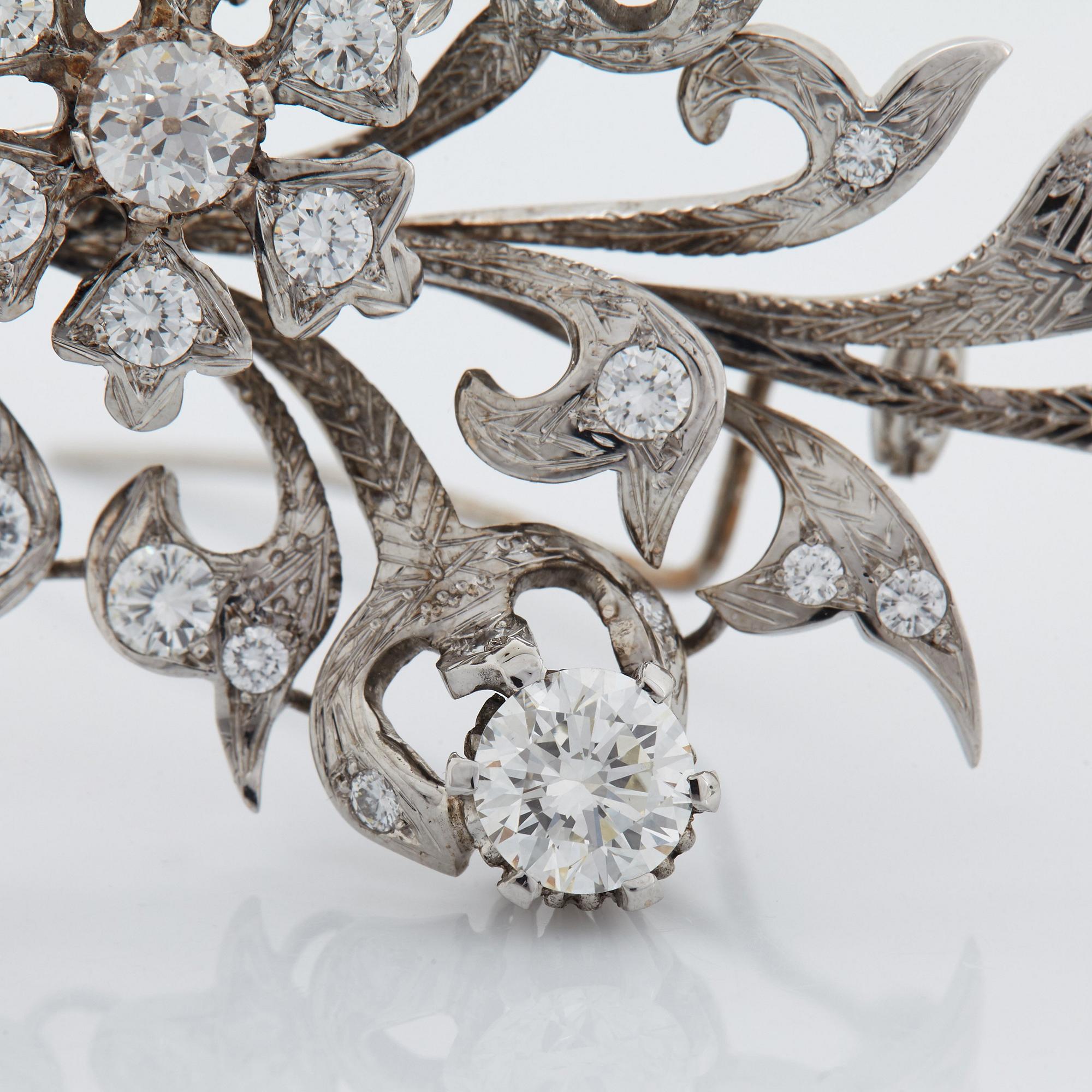 An 18K white gold brooch set with round brilliant-cut diamonds.