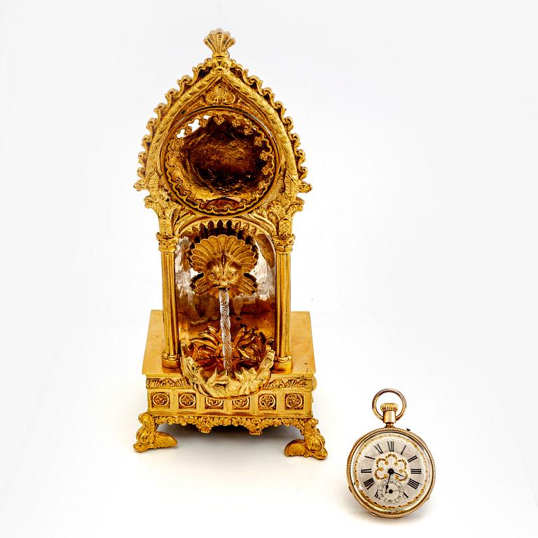 A mid 1800s gilded bronze pocket watch stand and pocket watch.