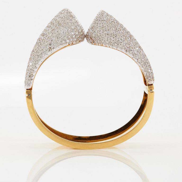 An 18K gold bangle set with round brilliant-cut diamonds.