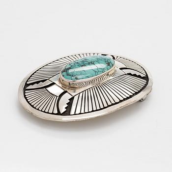 Chester Benally, a silver belt buckle with a turquoise, Navajo.