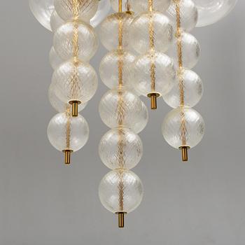 A 1970s brass ceiling light with glass shade. Height ca 144.