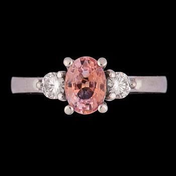 RING, rosa-orange fasettslipad safir med två briljantslipade diamanter, tot. ca 0.20 ct.