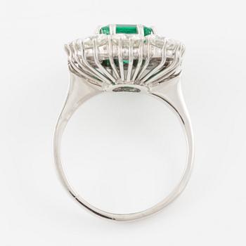 An 18K whitegold ring set with a step-cut emerald and round brilliant-cut diamonds.