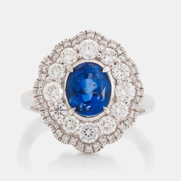 A platinum ring set with a faceted sapphire and round brilliant-cut diamonds.