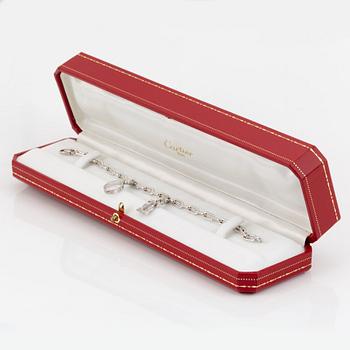 An 18K white gold Cartier "Spartacus" bracelet with two charms.