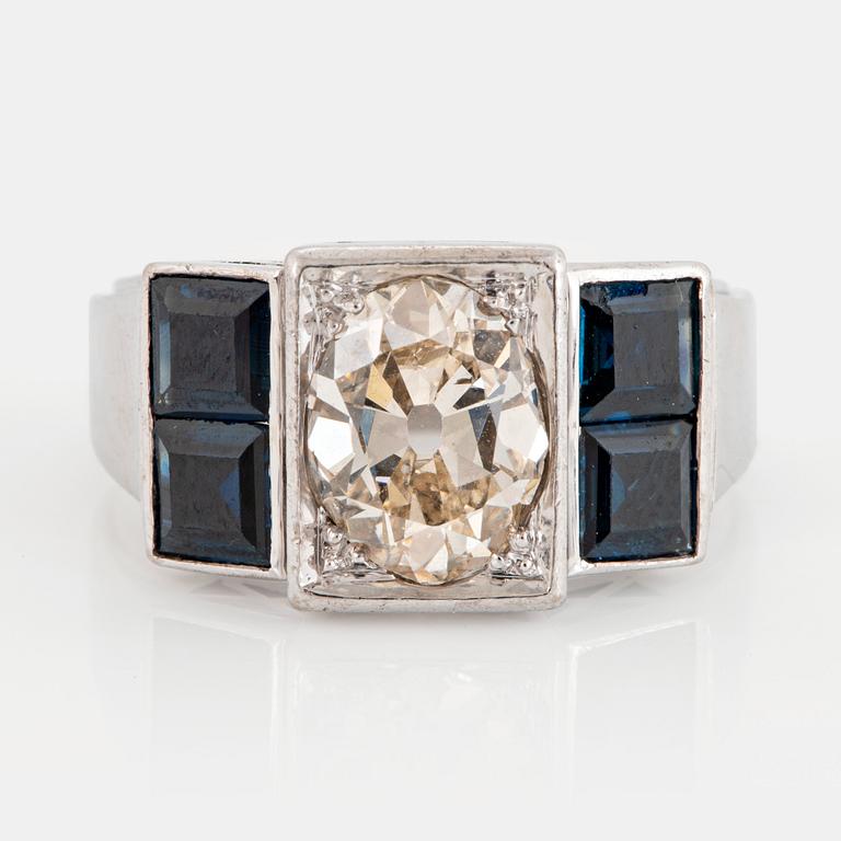 An 18K white gold ring set with an old-cut dimond weight ca 1.50 cts and step-cut sapphires.